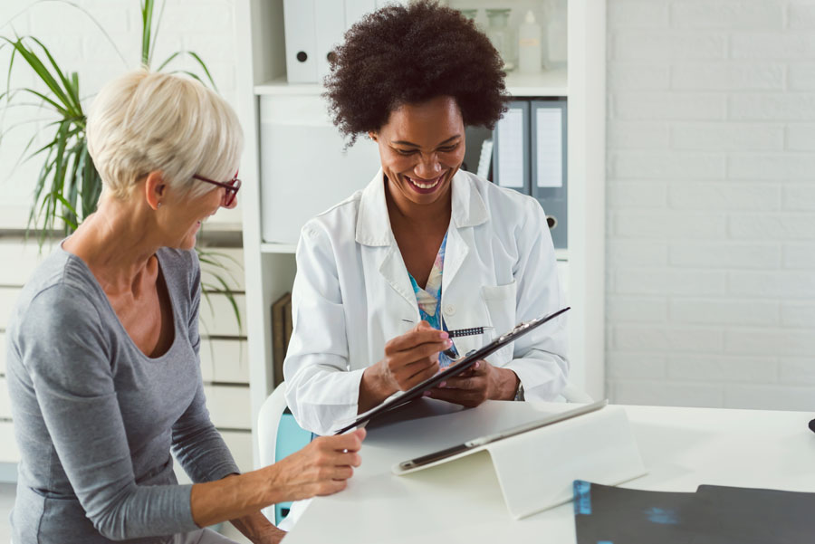 A specialist answers questions with an older adult during a spine and peripheral nerve consultation at UTMB Health.