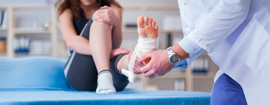 Female patient being treated for foot or ankle sprain by male doctor at UTMB Health.