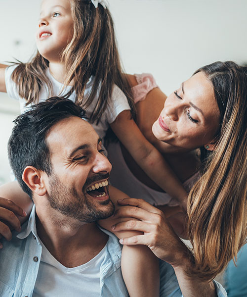 A dad, mom, and young daughter laughing together