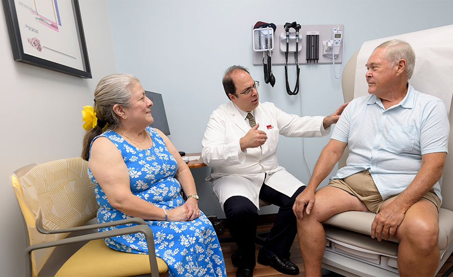 Dr. Hani Jneid consulting with male patient at UTMB Health, with his wife seated beside him