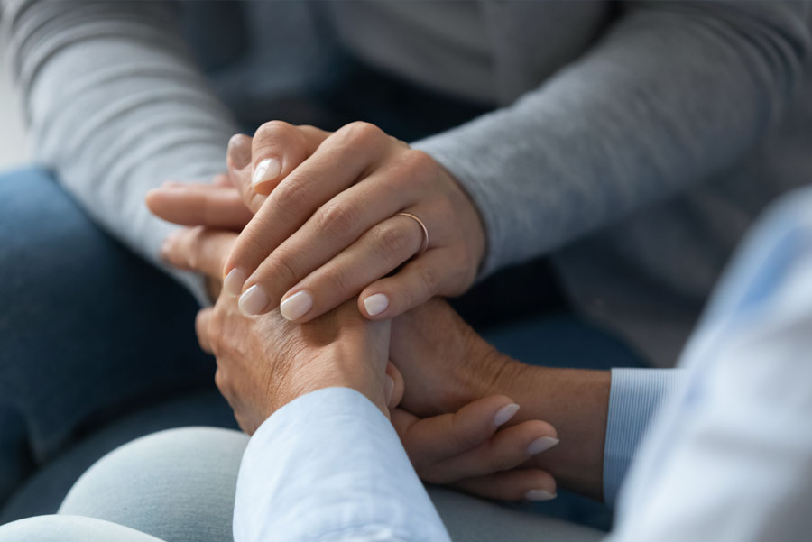 Adult daughter comforting old mom strokes holds her hand close up view. 
