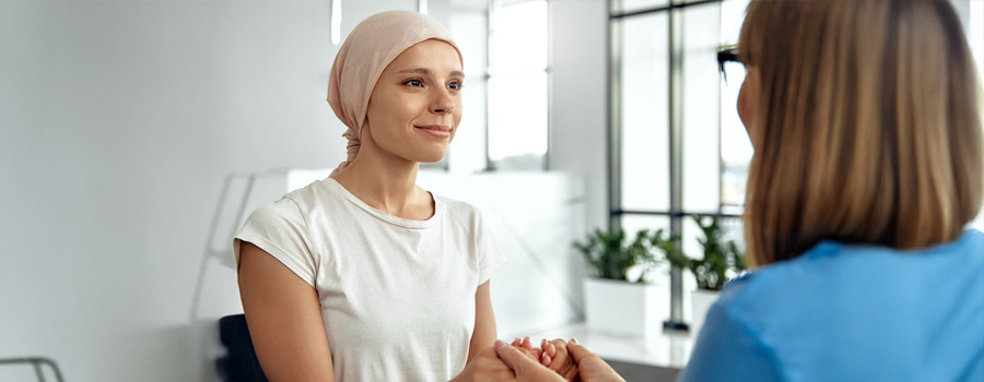 A young woman wearing a headscarf is smiling during a conversation with a healthcare provider.