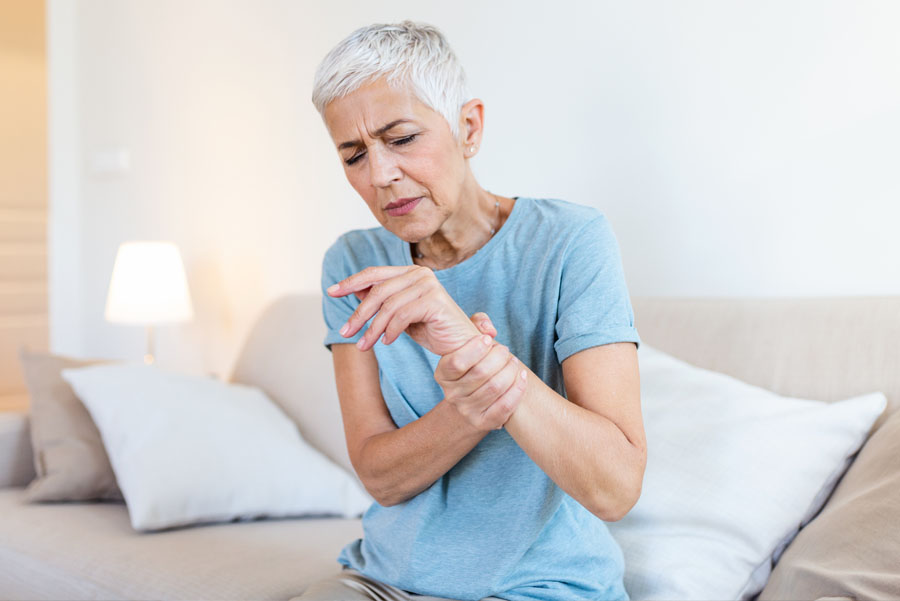 Seated elderly woman in arthritis pain, holding her wrist