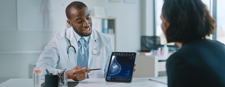Male doctor showing mammography test results on a tablet to female patient in a health clinic