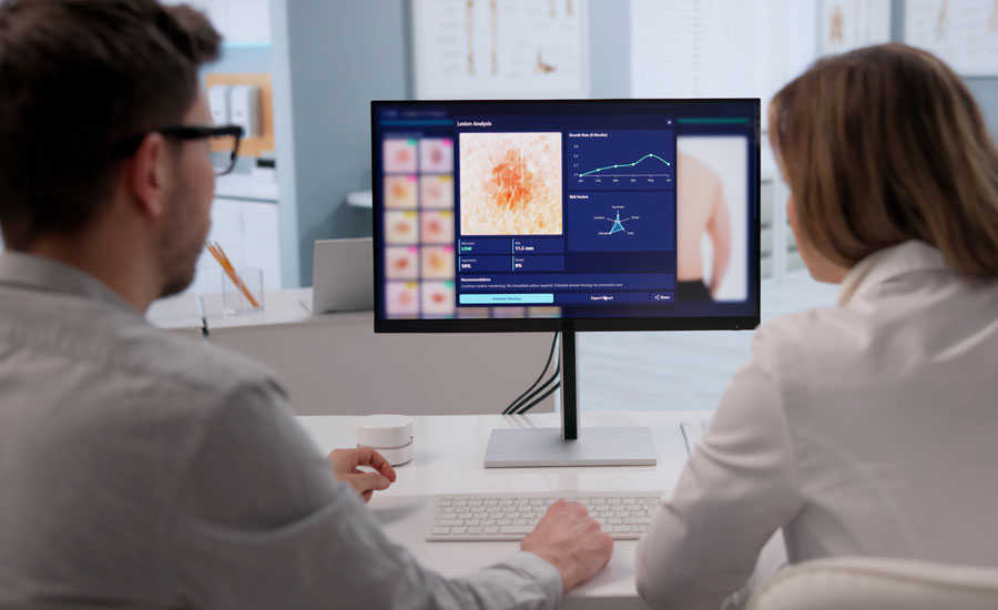 Back view of a male doctor and a female doctor viewing the results of a patient’s skin examination on a computer monitor