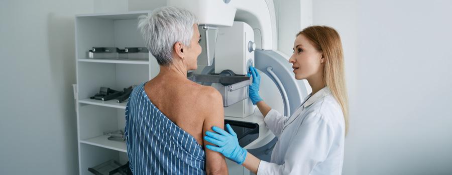 Senior woman having mammography scan at hospital with female medical technician