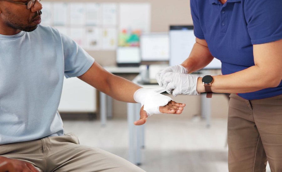 Woman wrapping man’s hand with gauze after burn injury