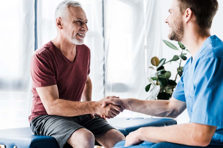 selective focus of happy patient shaking hands with doctor