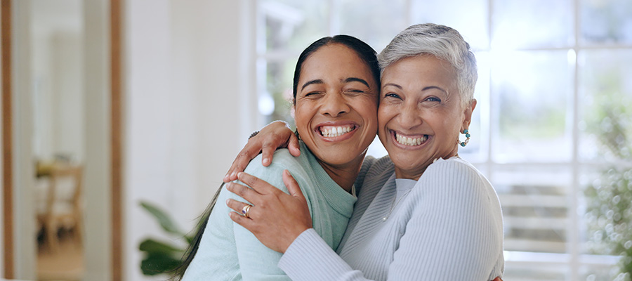Two women hug and smile, reflecting warmth and emotional support during menopause care.