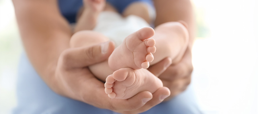 A UTMB Health provider holds the tiny feet of a newborn baby after delivery.