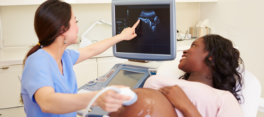A UTMB Health nurse points to a baby’s image on an ultrasound screen during a pregnancy visit.