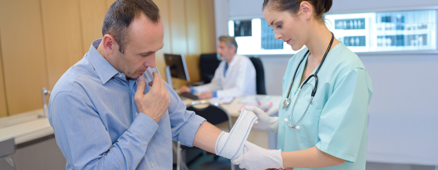 Female doctor wrapping a male patient’s wrist at hospital
