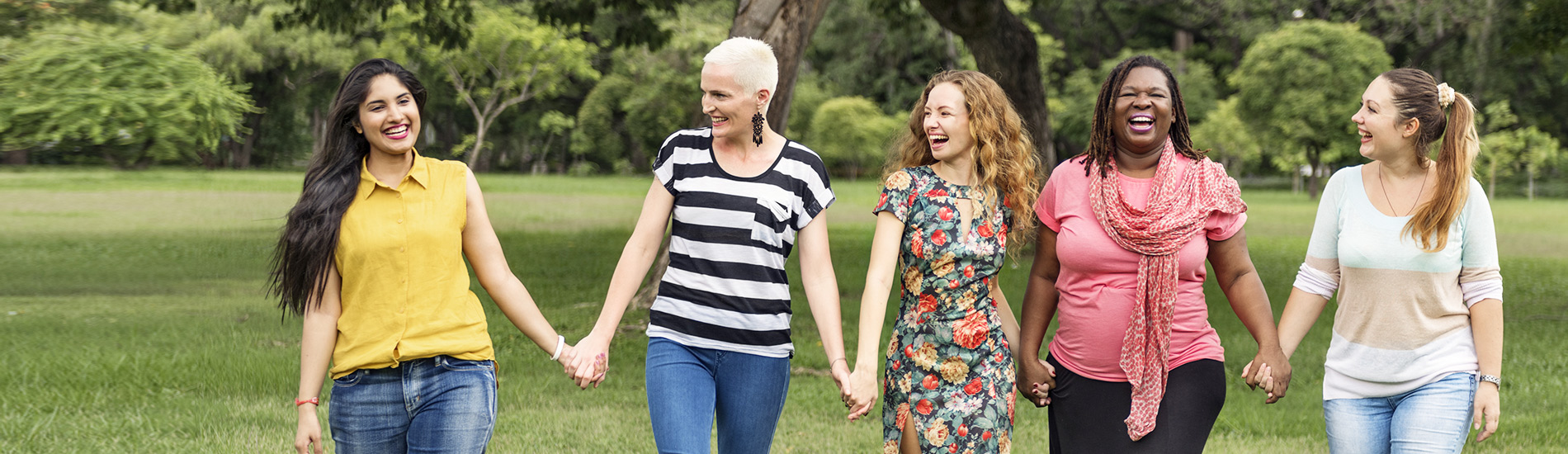 Five women holding hands and smiling