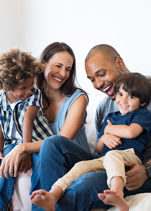 A mom, dad and two young boys sitting together and laughing