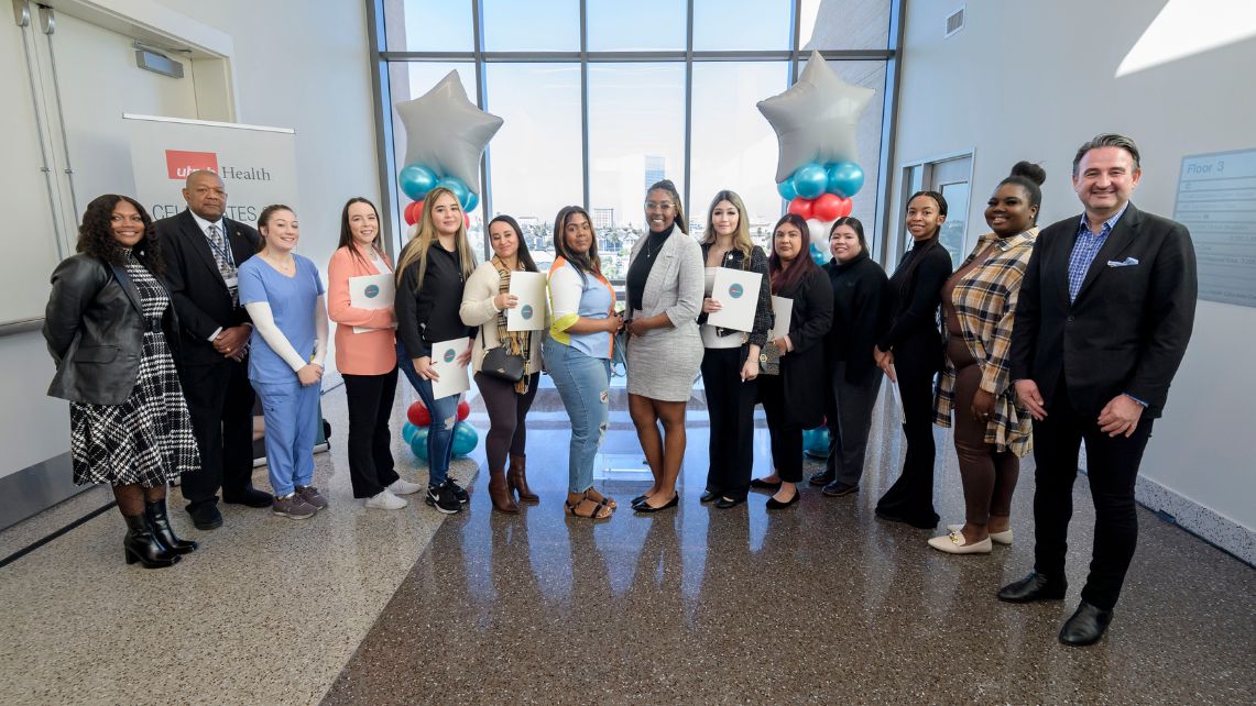 A group of UTMB women and men standing in front of star-shaped balloons celebrate the UTMB Registered Apprenticeship designation.