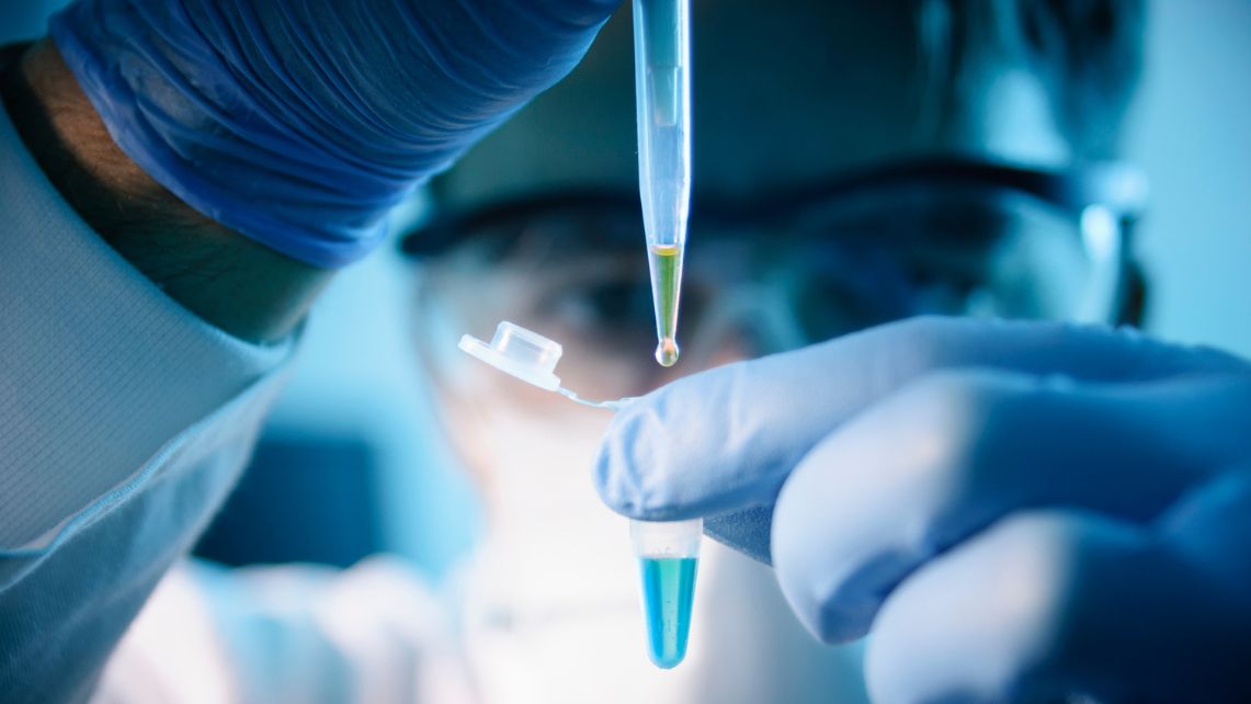 A researcher fills a small tube with blue liquid