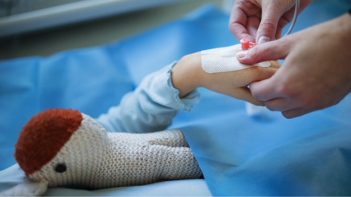 A child holds their toy while being treated by a health care provider