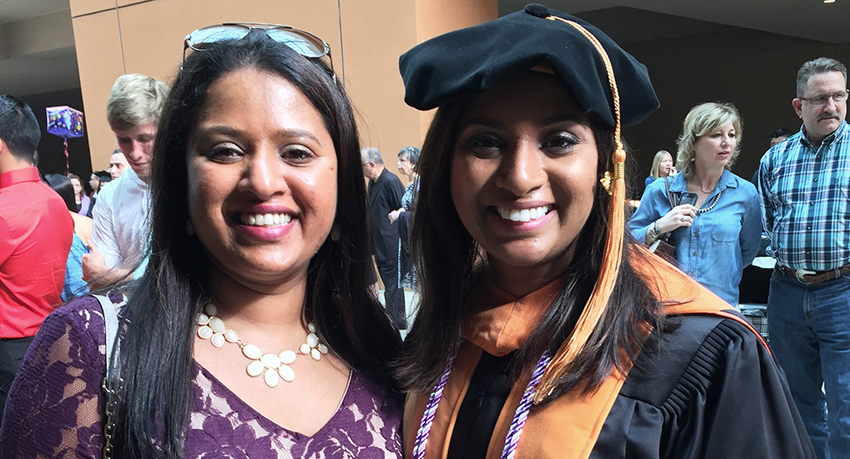 Two women, sisters, smile in a posed photograph taken at graduation.