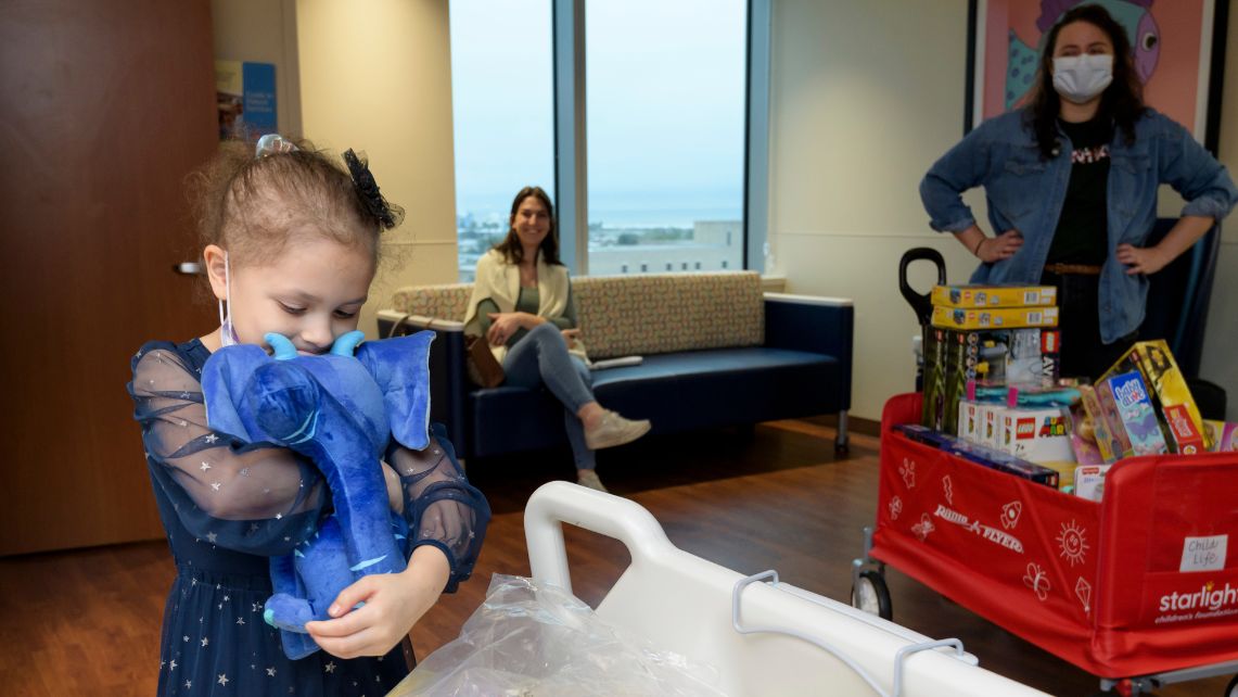 A young girl squeezes a stuffed toy donated by Tantrum Merch and nonprofit Starlight Children’s Foundation