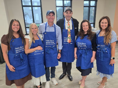 Galveston Mayor John Paul Listowski and crew prepare to take on tofu at the Oct. 5 class. Three people wearing blue UTMB aprons stand behind a table and hold a red octagonal STOP sign. Cooking supplies and food preparation materials are visible on the table.