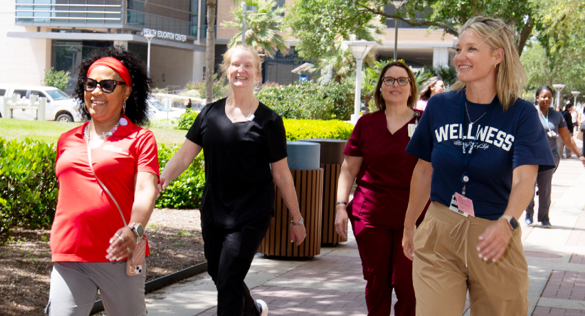 Four women walk along together during a Wellness Wednesday Walk on the UTMB campus