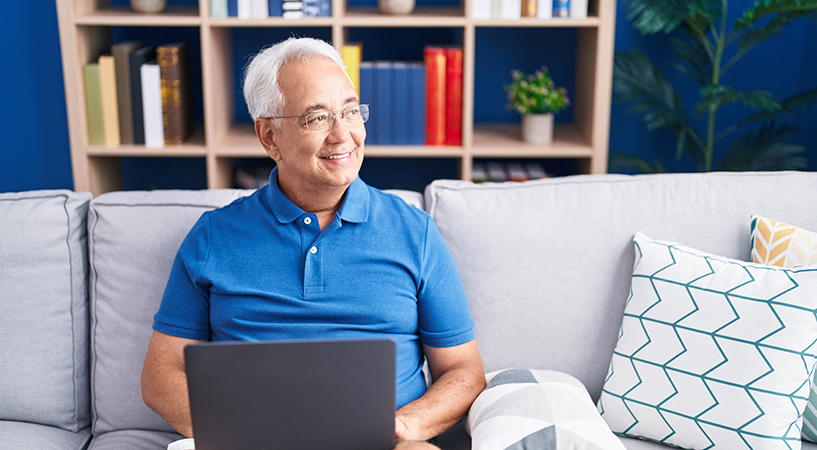 Man using a laptop computer looks up and smiles