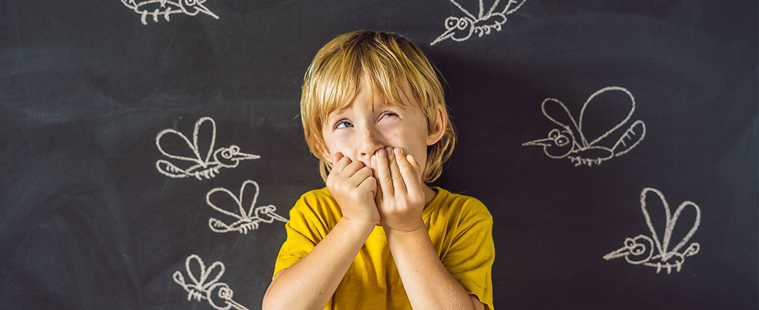 Child with chin in both hands standing in front of a dark background with white chalk drawings of insects