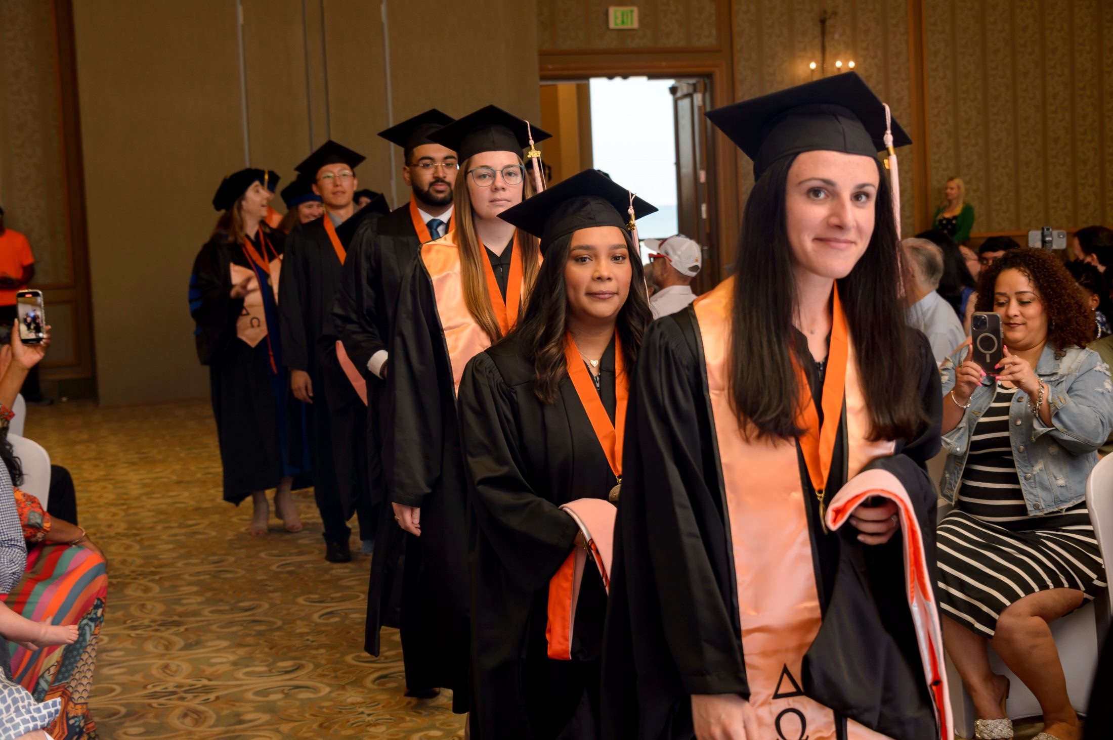 Graduates in caps and gowns enter in single file